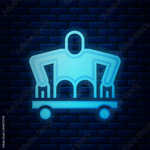 Glowing neon Man without legs sitting wheelchair icon isolated on brick wall background. Disability concept. Guy with physical disabilities. Vector