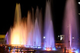 city fountain illuminated with green and yellow lights at night