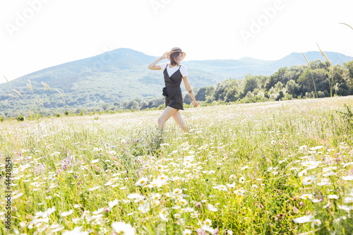 Beautiful young happy woman runs on the field of daisies