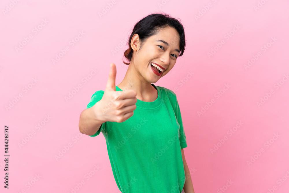 Young Vietnamese woman isolated on pink background with thumbs up because something good has happened Young Vietnamese woman isolated on pink background with thumbs up because something good has happened