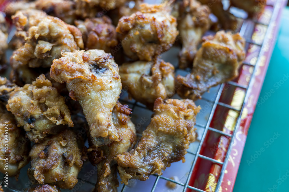 Plenty of pieces of chicken drumsticks are piled up on the grill.