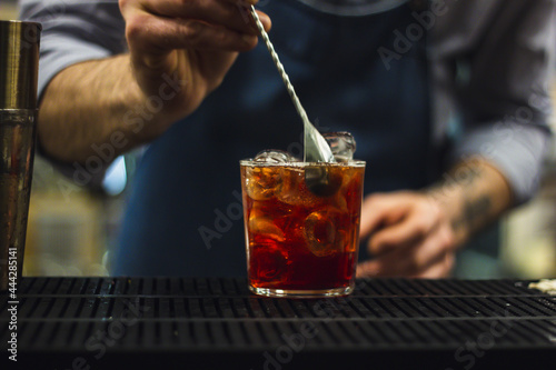 Bartender making cocktail with shaker and gin