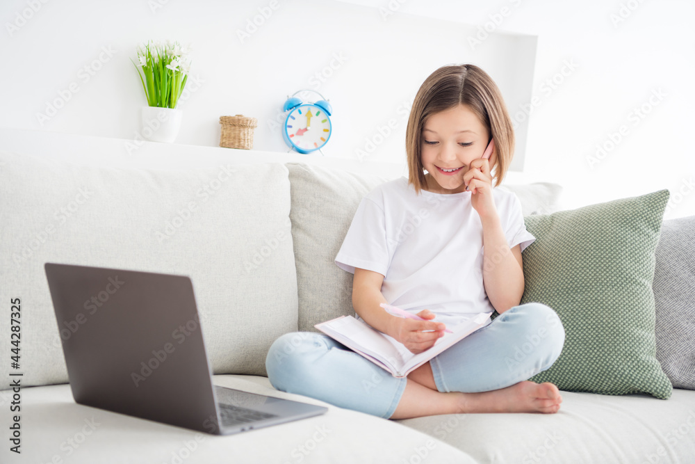 Photo portrait little girl sitting on couch talking writing notes in diary talking on cellphone Photo portrait little girl sitting on couch talking writing notes in diary talking on cellphone