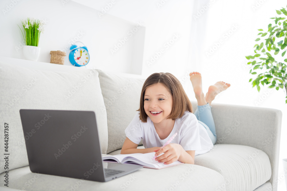 Photo portrait little girl laying on couch watch online lesson laughing keeping pen Photo portrait little girl laying on couch watch online lesson laughing keeping pen