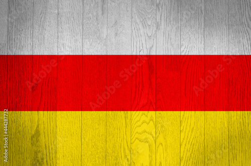 The flag of South Ossetia on a grunge wooden background.