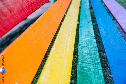 LGBTIQ+ concept. Multicolored park bench painted with rainbow colors to represent all collectives. LGBT Pride and gay pride day. Equality and respect for all background.