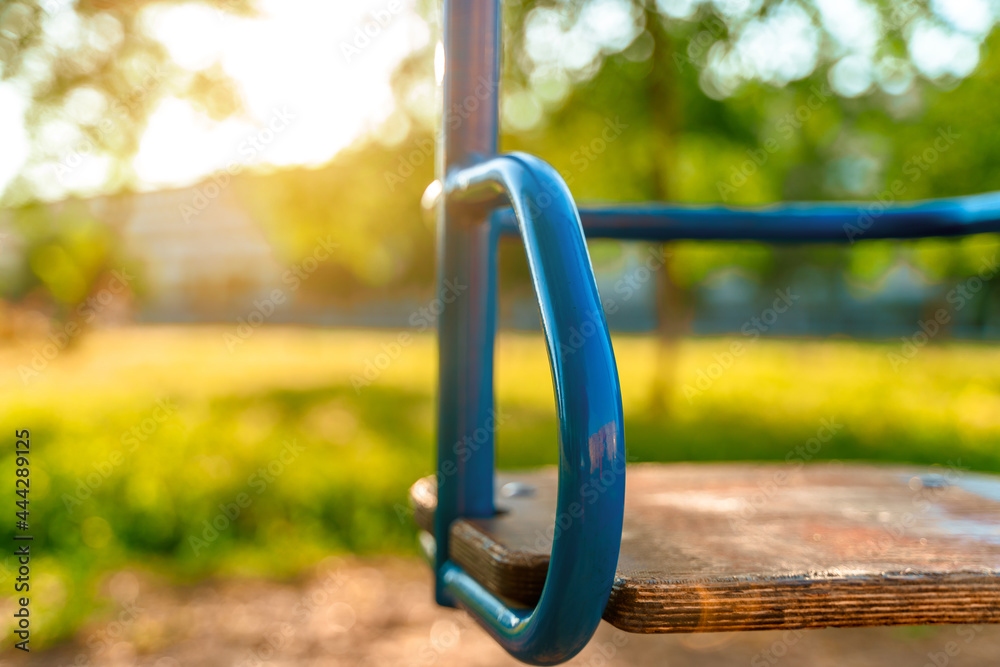 Children's swing in the park in summer at sunset. The concept of childhood