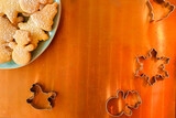 Christmas background with copy space: overhead of plate of homemade cookies covered with icing sugar and cookie cutters (rocking horse, snowman, snowflake) on copper  background