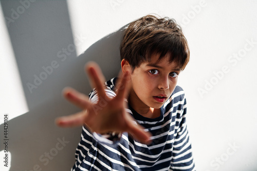 Scared kid with stop gesture suffering from domestic violence