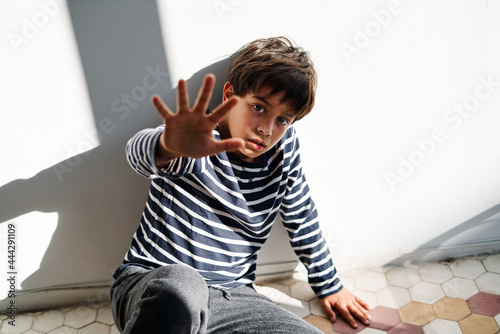 Scared kid with stop gesture suffering from domestic violence