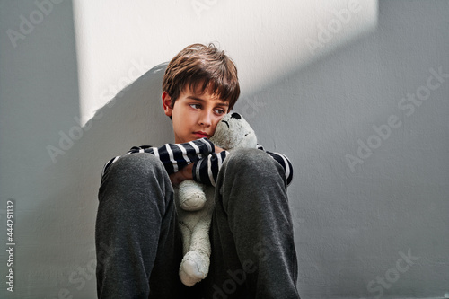 Sad boy with toy sitting on floor