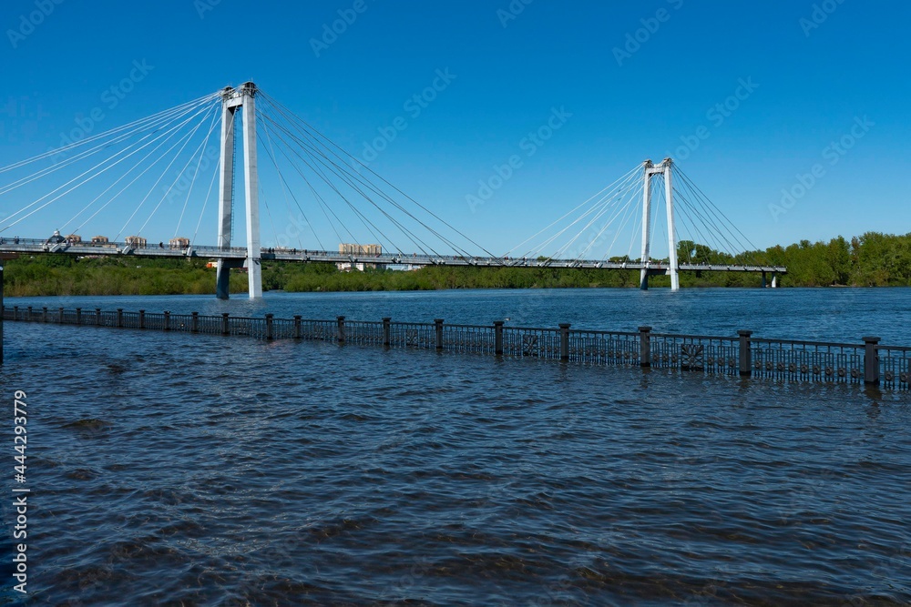 Flooded embankment with a large suspended bridge in the background.