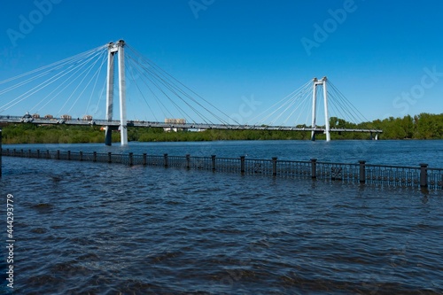 Flooded embankment with a large suspended bridge in the background. © Vectorina