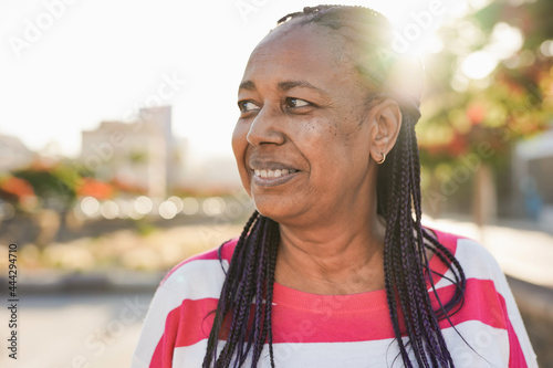 Happy senior african woman in the city with sunset in background