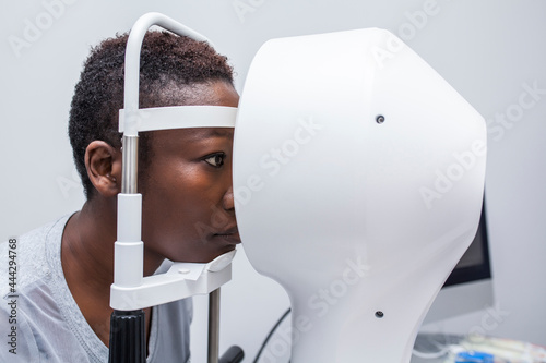Black woman in optometry cabinet using a modern corneal topographer