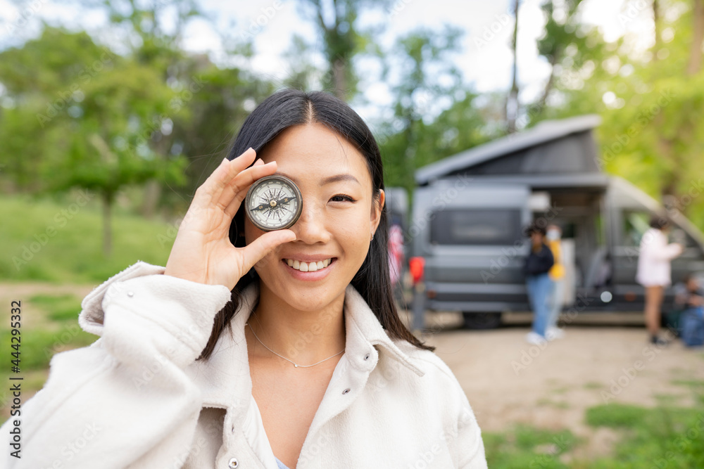 Cheerful Asian female traveler playing with compass Cheerful Asian female traveler playing with compass