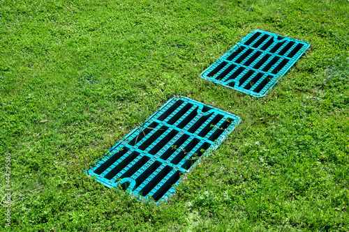 manhole drainage grates on the lawn with green grass septic tank cover, sump cesspool drainage system environment design side view with copy space, nobody. photo