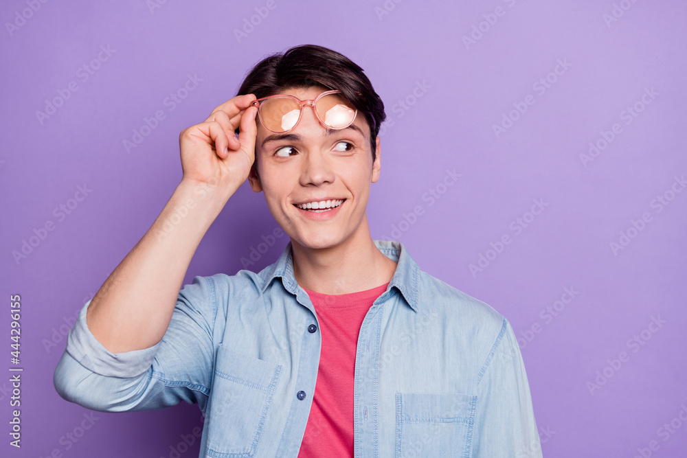 Photo of young guy happy positive smile interested dream look empty space isolated over purple color background Photo of young guy happy positive smile interested dream look empty space isolated over purple color background