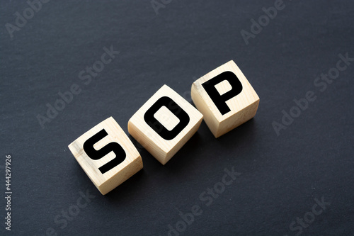 SOP - acronym from wooden blocks with letters, abbreviation SOP standard operating procedure concept, black background