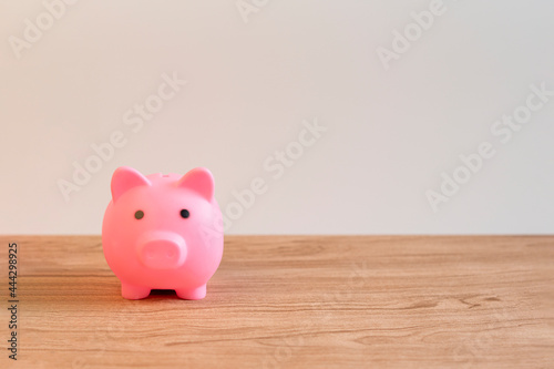 A pink piggy bank on wooden and white background. Saving money concept.
