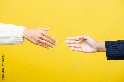 Closeup shot of human holding hands isolated on yellow studio background. Concept of human relations, friendship, partnership, family. Copyspace.