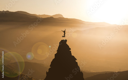 Young Woman jumping On top Of Mountain Peak Celebrating Success. Businesswoman Climber success and goal achievement Concept. Cliff Climbing Adventure. Sunset mountains, Female silhouette photo