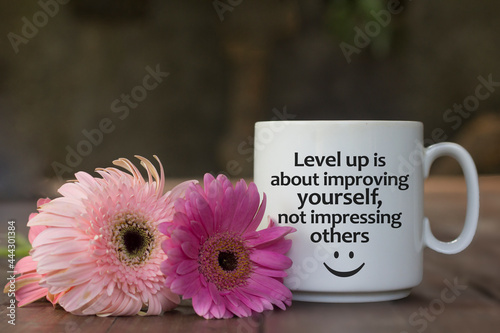 Inspirational message on a white mug - Level up is about improving yourself, not impressing others. With cup of coffee and two pink daisy flowers background. Self improvement and confidence concept.