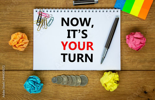Now it is your turn symbol. Words 'Now it is your turn' on white note. Wooden table, colored paper, paper clips, pen, coins. Business, Now it is your turn concept. Copy space.
