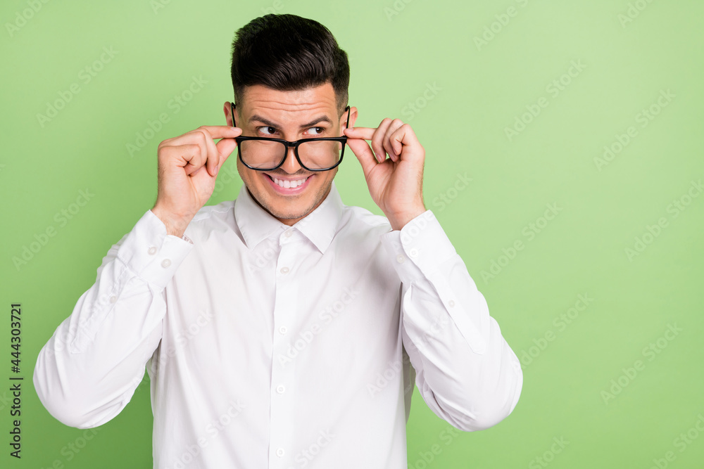 Photo of pretty funny young gentleman wear white shirt arms spectacles looking empty space isolated green color background Photo of pretty funny young gentleman wear white shirt arms spectacles looking empty space isolated green color background