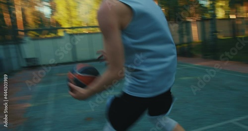 American basketball player cool guy fast moving dribbling throwing ball into hoop on court outdoors