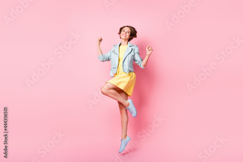 Photo of dreamy inspired lady jump have fun wear yellow short dress sneakers isolated pink color background