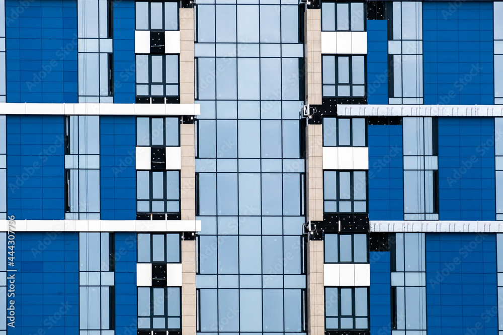 Close-up of many windows on blue exterior of modern apartment building. For real estate Background.