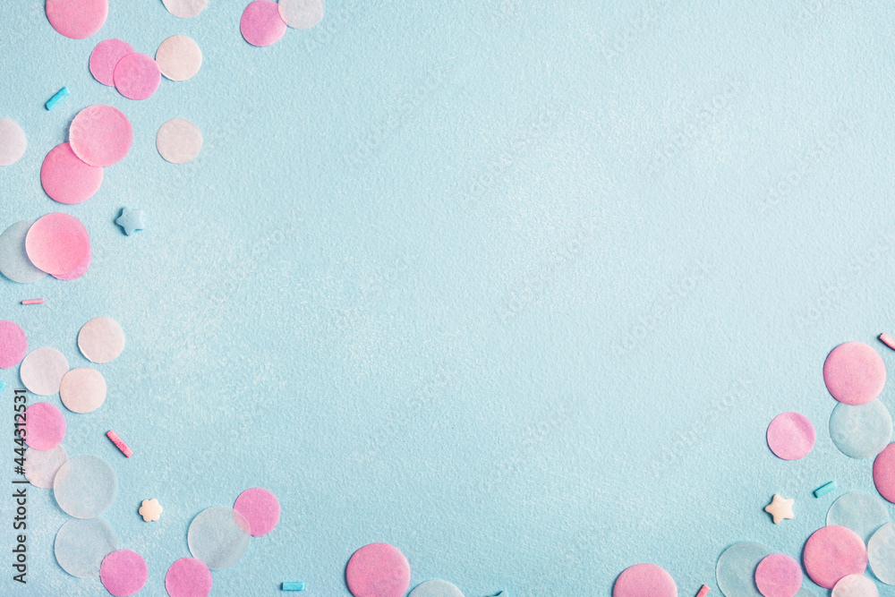 Birthday or party background. Colorful confetti on pastel blue surface. Top view, flat lay, copy space, frame