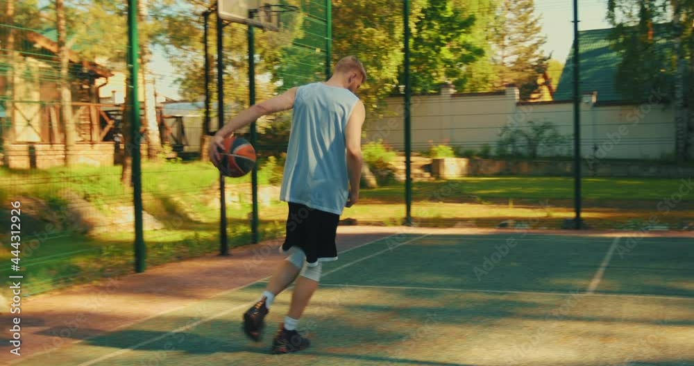 Cool young guy sportsman basketball player go to court and score ball in hoop outdoors in summer Cool young guy sportsman basketball player go to court and score ball in hoop outdoors in summer