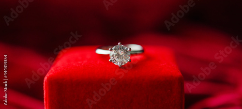 Diamond ring with jewelry gift box on red fabric background photo