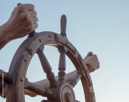 Steering hand wheel ship on sky background, hand hold hand wheel photo