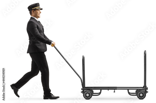 Full length profile shot of a bellboy walking and pushing a trolley cart photo