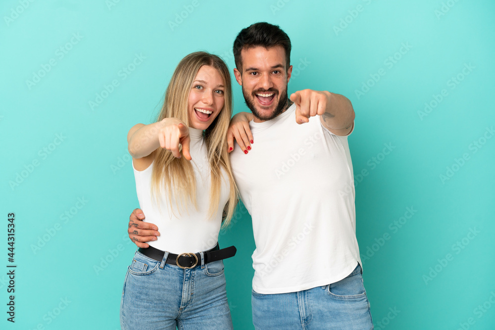 Young couple over isolated blue background points finger to the front Young couple over isolated blue background points finger to the front