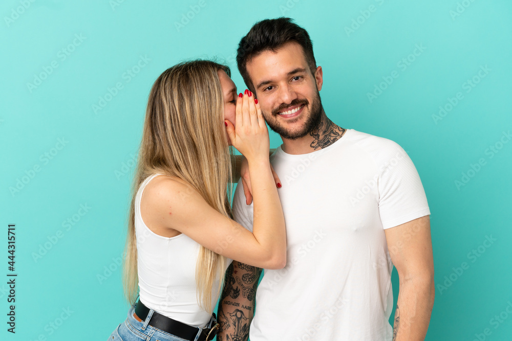 Naklejka premium Young couple over isolated blue background whispering something
