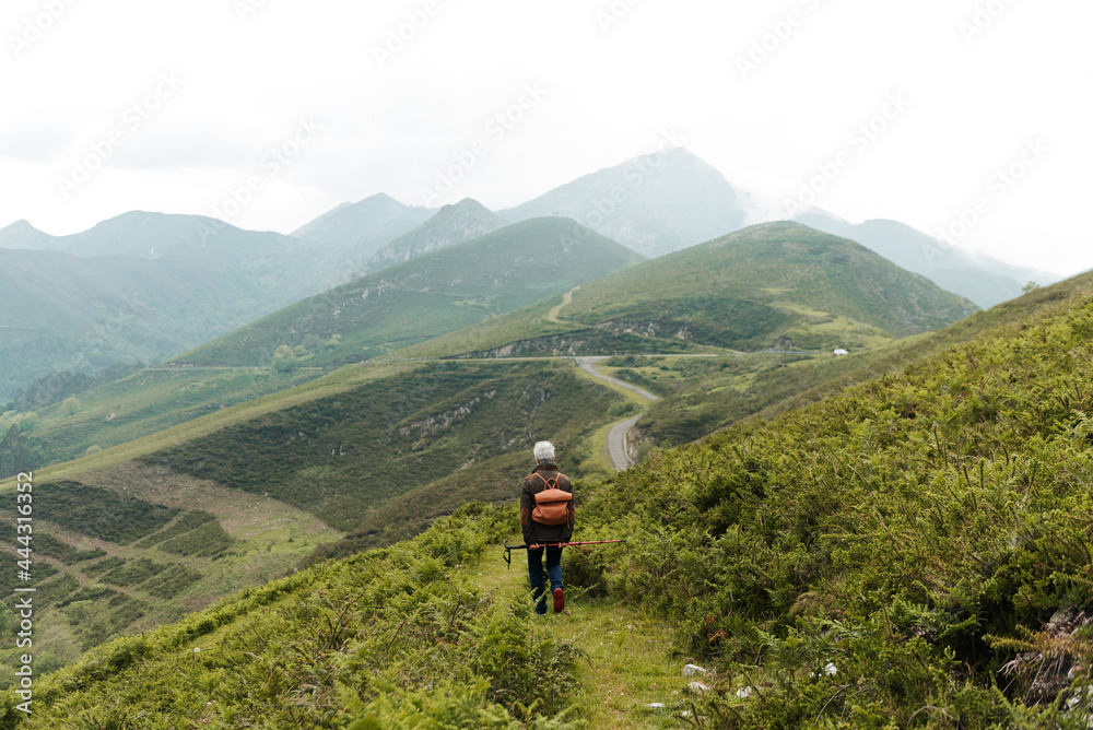 Unrecognizable senior female traveler walking towards mountain Unrecognizable senior female traveler walking towards mountain