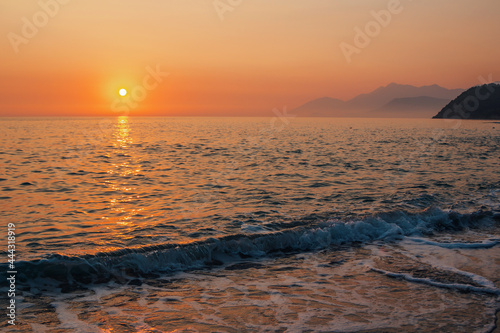 Beautiful landscape - beach on sunset -red and orange sky and sunlight reflecting on sea water.