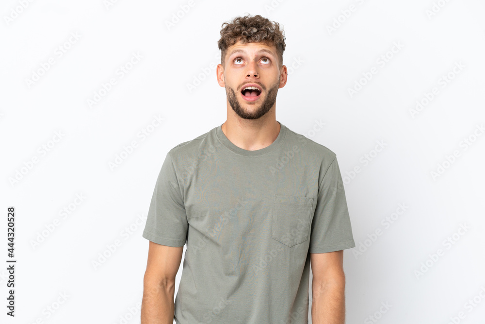 Obraz premium Young caucasian handsome man isolated on white background looking up and with surprised expression