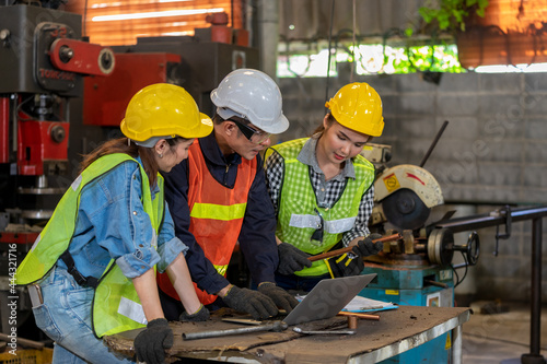 Industrial engineers have consult with femal colleagues while using laptop.