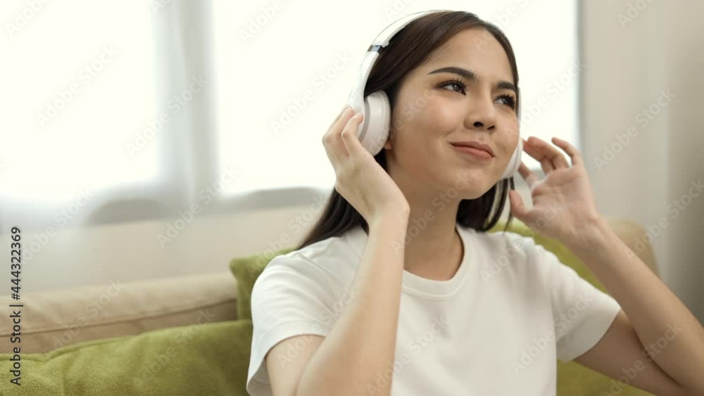 Relaxing time on sofa. Beautiful young asian woman sitting on sofa she choose music from smartphone take a rest and listening song with headphone. Lifestyle in living room at house in the morning. Relaxing time on sofa. Beautiful young asian woman sitting on sofa she choose music from smartphone take a rest and listening song with headphone. Lifestyle in living room at house in the morning.