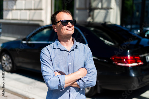 Caucasian man forty years old businessman in the city in the summer on the background of the car