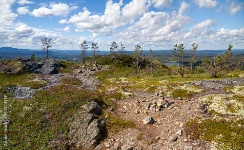 Tourist route to the top of Kivakka. A rocky path among the rocky boulders overgrown with moss. Green tundra with rare low trees. There's a taiga on the horizon. National Park "Paanayarvi". Karelia