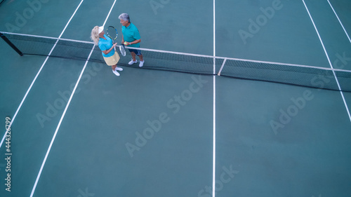 Overhead view of senior couple playing tennis on sunny day. © TRAVEL EASY