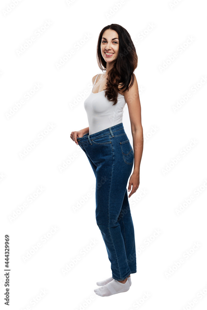Young woman in jeans one size up. Happy beautiful brunette. Healthy lifestyle and slimness. Full height. Isolated on white background. Vertical. Young woman in jeans one size up. Happy beautiful brunette. Healthy lifestyle and slimness. Full height. Isolated on white background. Vertical.