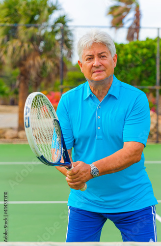 Senior man playing tennis on sunny day. © TRAVEL EASY