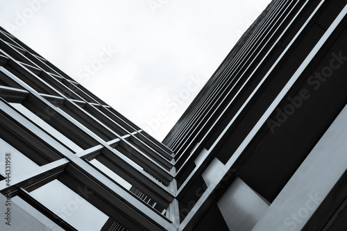 Looking up shot of a business building. A cold monochrome structure giving a V like form towards a bright white sky. 